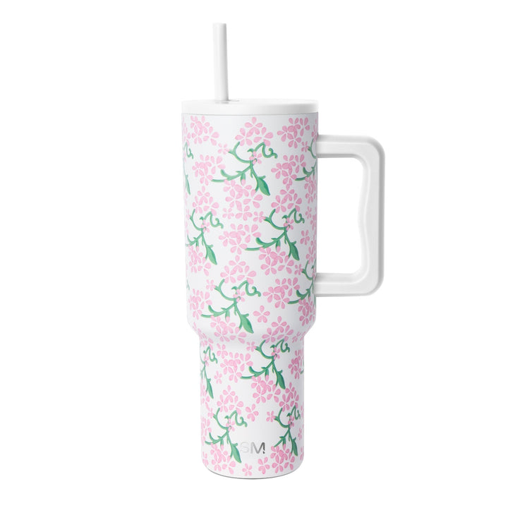 White insulated tumbler with handle and lid featuring pink flowers and green foliage pattern, Simple Modern logo, against white background.